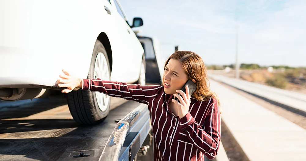 Das Fahrzeug steht auf dem Abschlepper und Frau ruft an